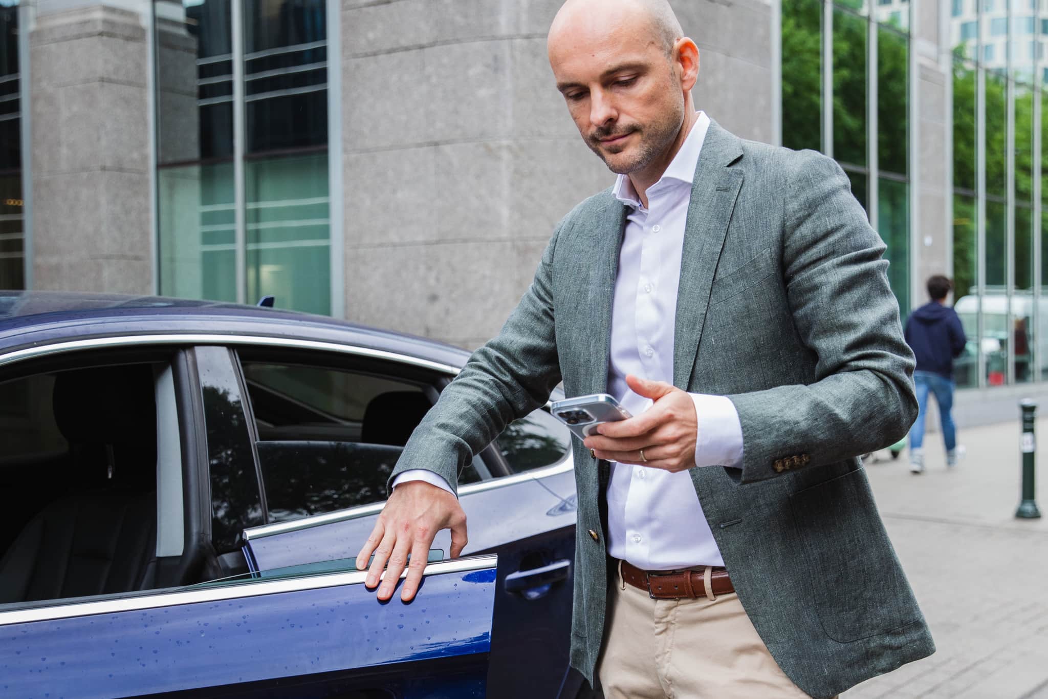 Man getting out of car to submit his milage allowance on his phone 