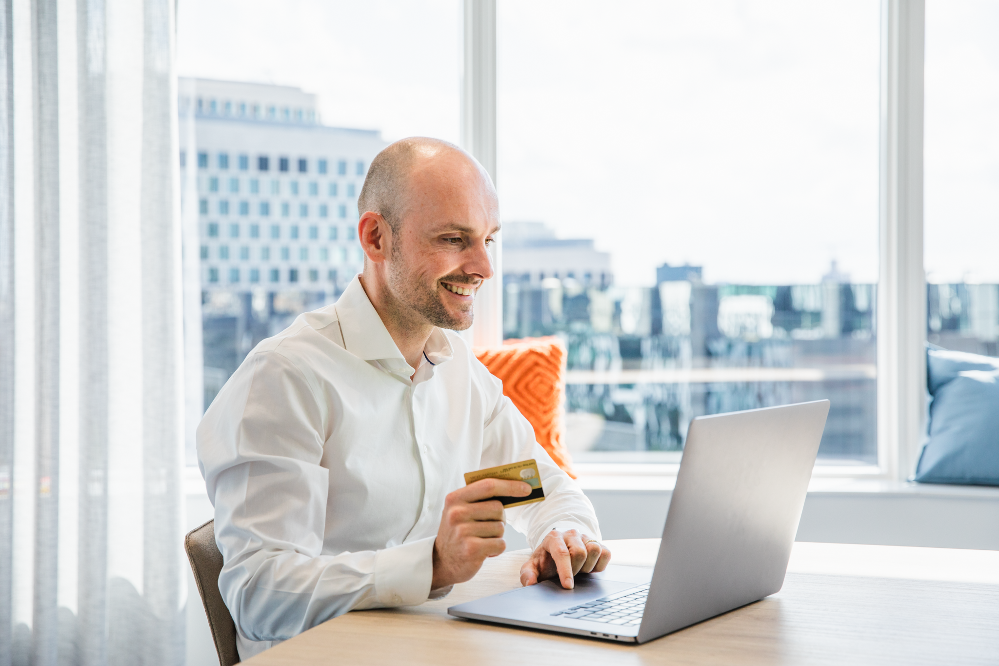 Man looking happy holding credit card and working on computer